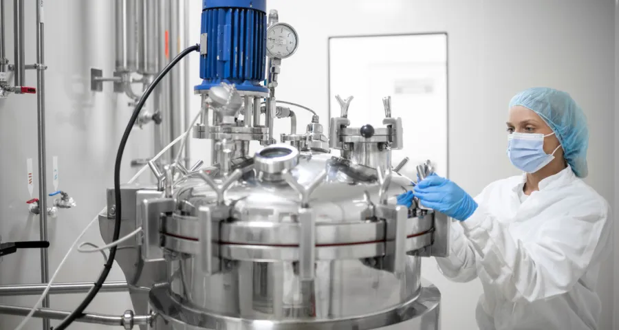 Technician operating a stainless steel reactor in a cleanroom